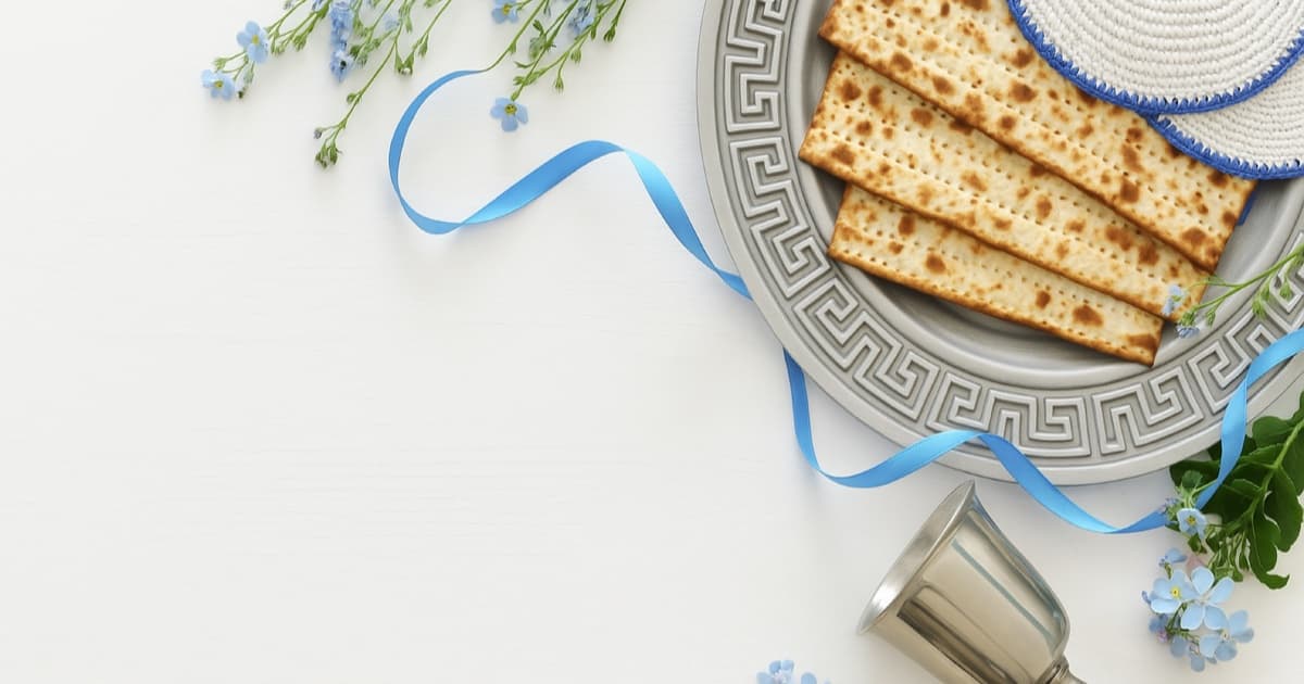 Passover Seder plate with matzah, silver kiddush cup, and spring flowers