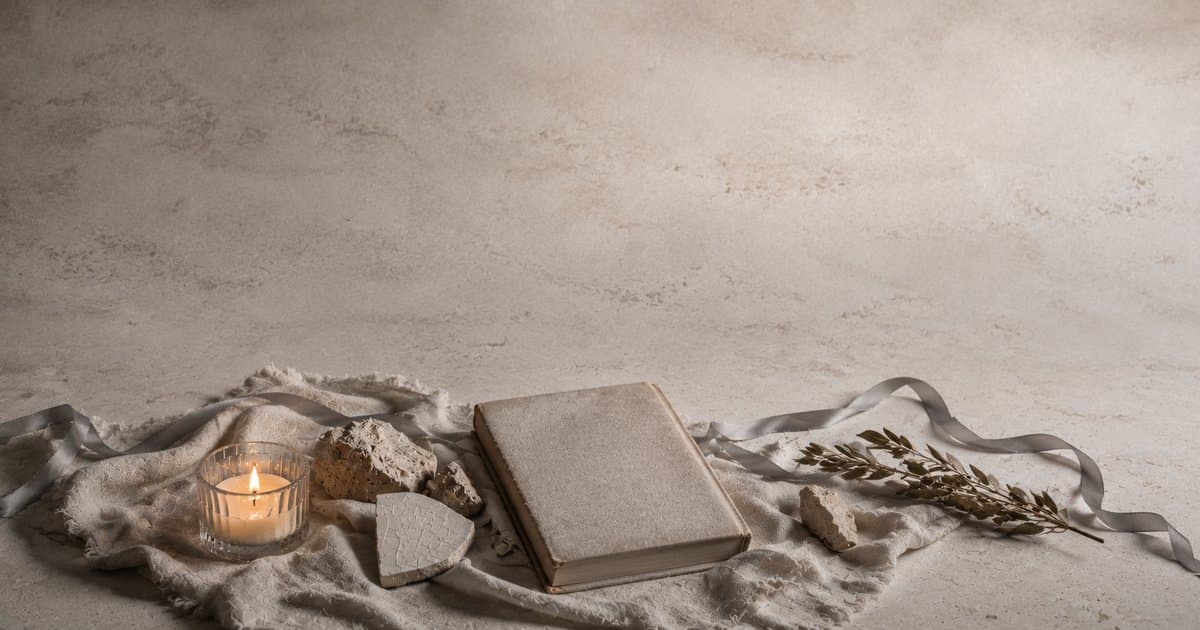 Cena de luto de Tishá BeAv com vela memorial única, livro de Lamentações fechado, linho rasgado e espigas secas sobre pedra